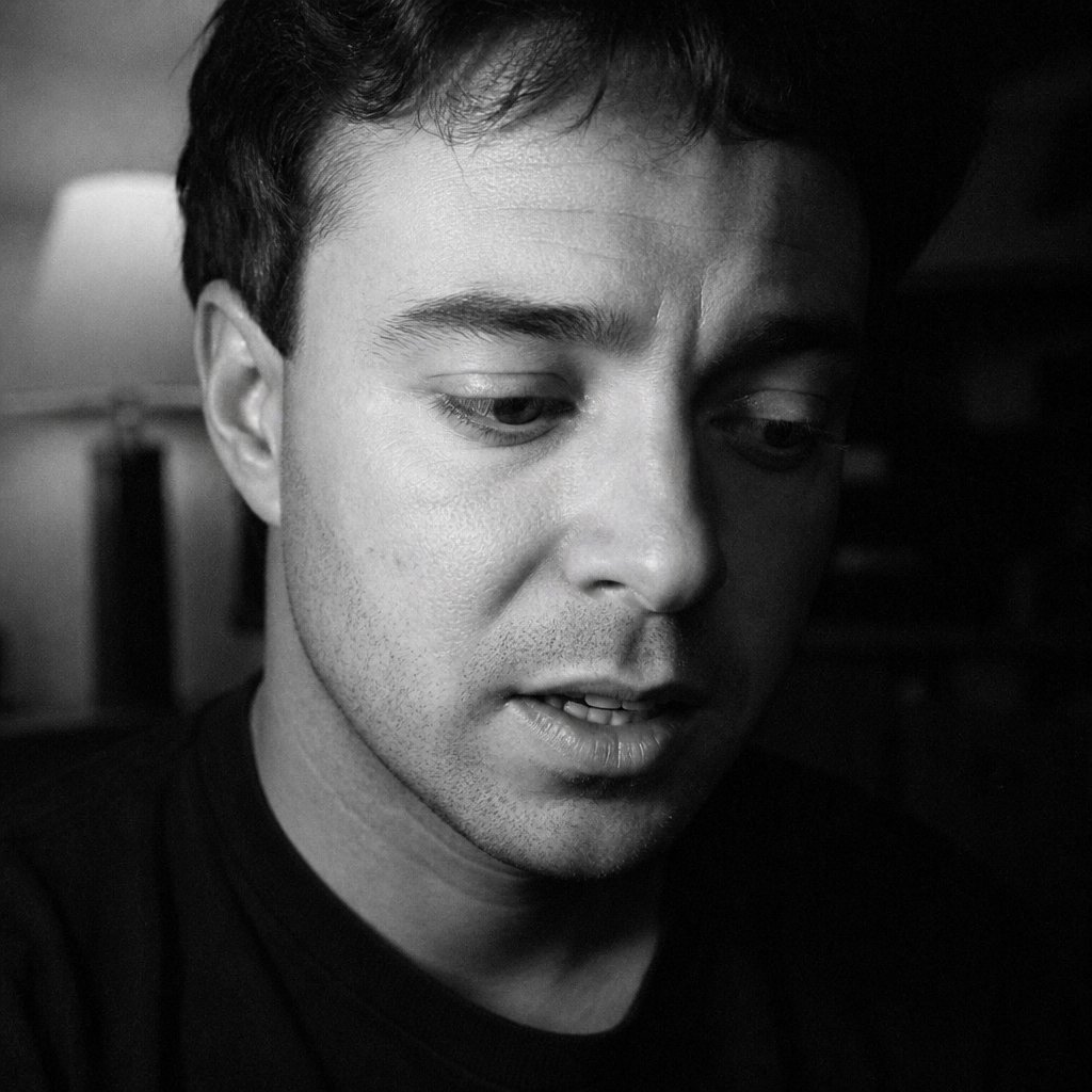 Close-up of a man speaking with his eyes cast down and away